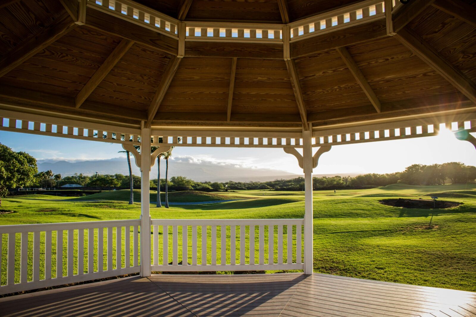 Serene view from a gazebo overlooking a lush golf course at sunset, capturing peaceful outdoor leisure.
