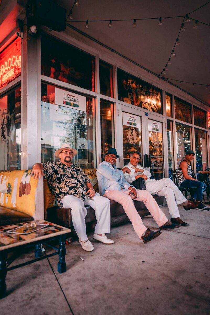 Elderly men sitting and enjoying each other's company outside a vibrant Miami cigar lounge.